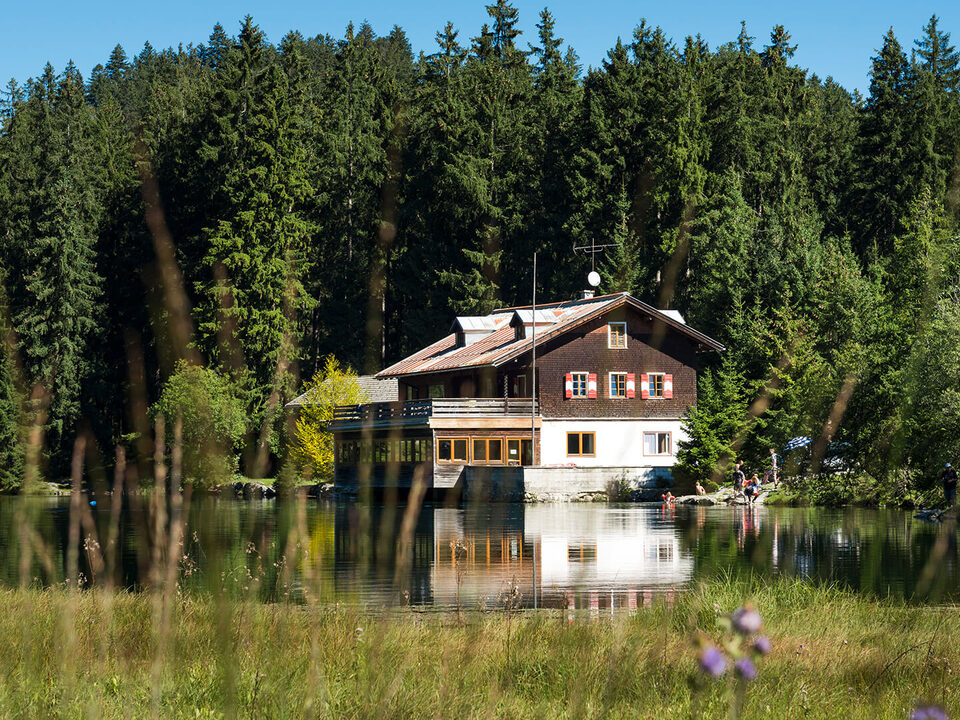 Locanda sul lago davanti a un pendio boscoso