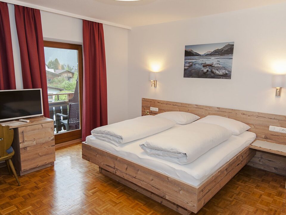 Letto matrimoniale con scrivania, televisore e tende rosse