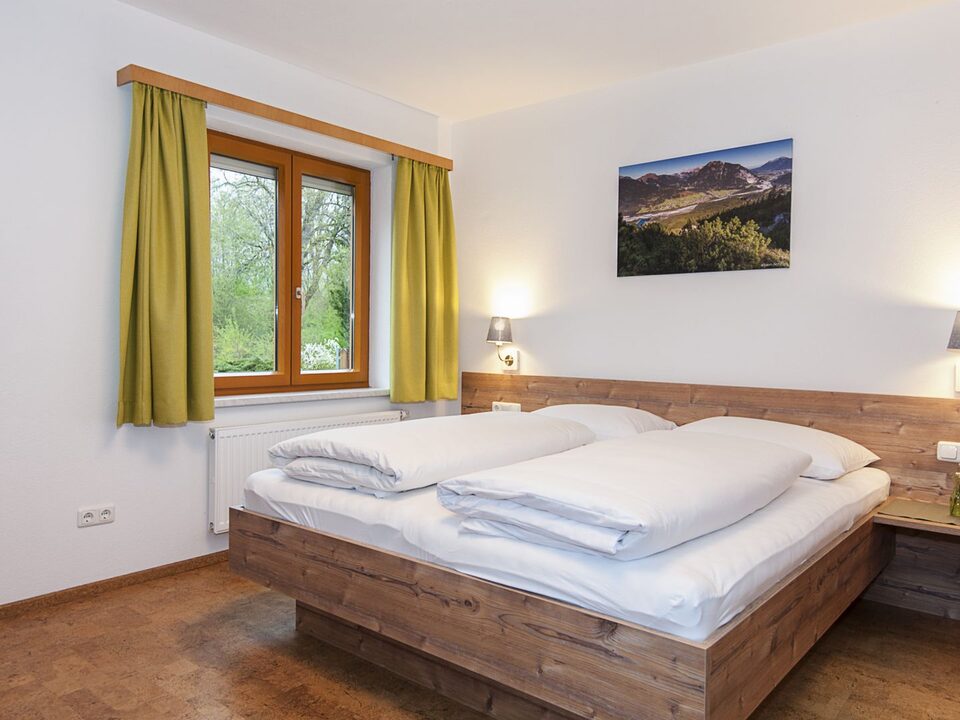 Kamer met houten bed, wandspiegel en groene gordijnen