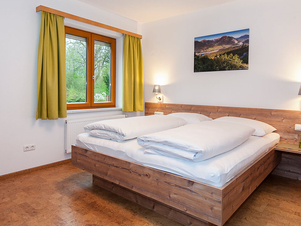 Camera doppia con pavimento in legno e tende verdi